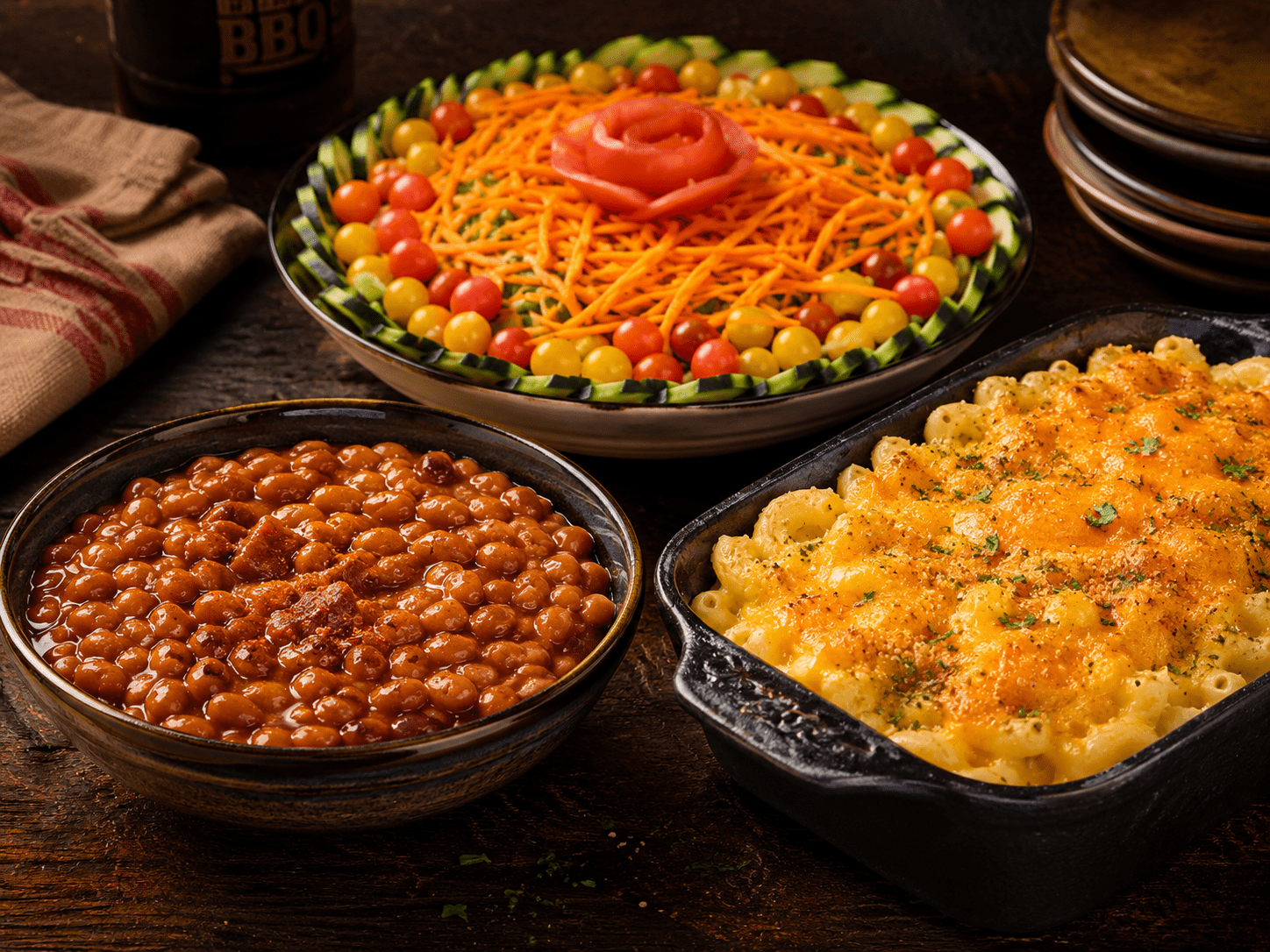 BBQ side dish spread with baked beans, mac and cheese, and fresh salad on a rustic table