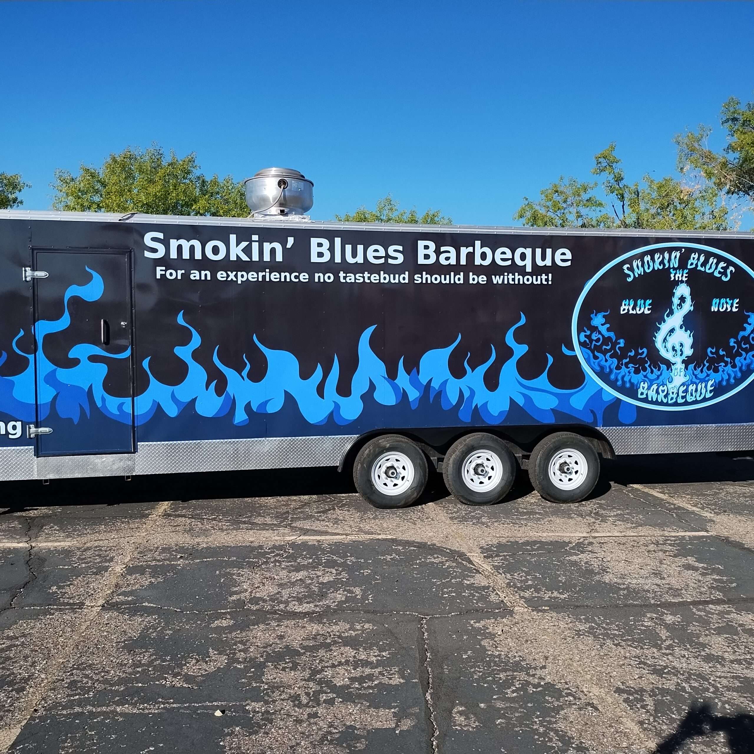 Smokin’ Blues Barbeque food trailer with blue flame graphics and custom branding parked outdoors